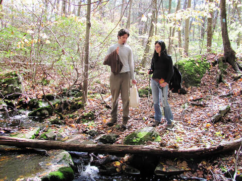 Karen Seto and Peter Christensen talking near a stream in the Yale-Myers Forest